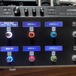 Černý kytarový efektový pedalboard s nápisem LINE 6 HX EFFECTS. Horní část obsahuje ovládací knoflíky a tlačítka SAVE, ACTION a HOME. Spodní část obs…