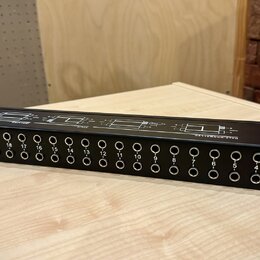 Černý rackový patchbay s řadou 24 zapojovacích jackových konektorů. Nad konektory jsou bílé nápisy s čísly od 1 do 24 a technické schéma zapojení. Na…