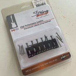 Plastové balení s náhradními kobylkovými sedly a šrouby. Na obalu je nápis String SAVER, High Performance Saddles, Dramatically reduces string breaka…