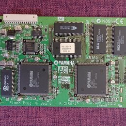 Zelená elektronická deska s osazenými čipy a součástkami. Na desce jsou viditelné nápisy YAMAHA, AP for XG a Plug for XG. V dolní části je text Piano…