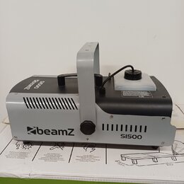 Šedý a černý efektový přístroj s úchytkou. Na přední straně je bílé logo beamZ a nápis SI500. Horní strana obsahuje černý ovládací panel s knoflíkem…