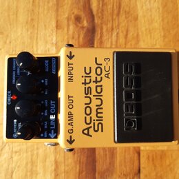 Zlatý kytarový efekt s černým spínacím pedálem. Na horní straně je nápis Acoustic Simulator AC-3 a logo BOSS. Zařízení má čtyři černé ovládací knoflí…