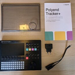 Na fotografii je černý sekvencer Polyend Tracker + s displejem a řadou tlačítek. Součástí sady je průhledný plastový kryt, napájecí adaptér a printed…