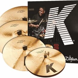 Sada čtyř mosazných činelů značky Zildjian z řady K. Na činelech jsou nápisy Custom Dark Ride, Custom Dark Crash (dvakrát) a Custom Dark Hi Hat Ride.…
