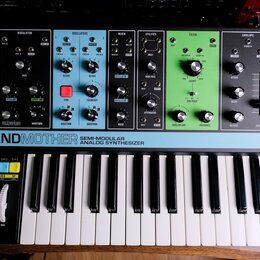 Černý semi-modulární analogový syntetizátor s klaviaturaí, který má v horní části barevně rozdělené sekce: žlutou (ARP/SEQ), černou (MODULATION), mod…