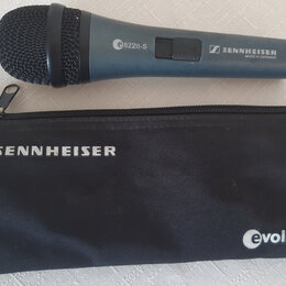 Modrý dynamický mikrofon s černou mřížkou a černým pouzdrem. Na těle mikrofonu je bílý nápis e822II-S a logo SENNHEISER s doplňkem MADE IN GERMANY. N…