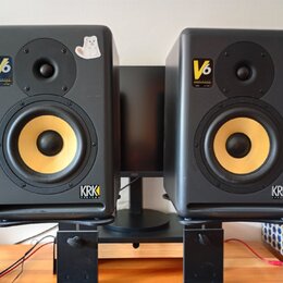 Pár černých studiových monitorů s žlutými membránami basových reproduktorů. Na obou je vidět nápis V6 a logo KRK SYSTEMS. Levý reproduktor má v horní…