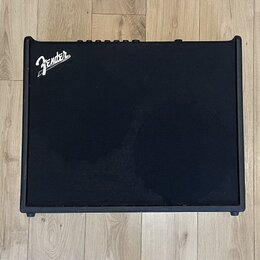 Černý kytarový kombo zesilovač s texturovaným povrchem. V levém horním rohu je bílé logo Fender. Horní hrana obsahuje ovládací prvky v podobě několik…