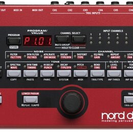 Červený perkusní syntetizátor s nápisem nord drum 2 modeling percussion synthesizer. Zařízení má digitální displej zobrazující hodnotu P1.01, několik…