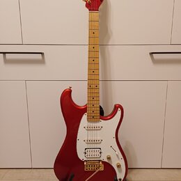 červená elektrická kytara s jasným lakem a hnědým hmatníkem. Na hlavě je zlatý nápis Ibanez a na těle se nachází bílý pickguard s třemi snímači. Kyta…