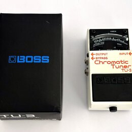 Bílá kytarový ladič s černým pedálem a displejem. Na přístroji jsou nápisy „OUTPUT“, „BYPASS“, „INPUT“, „Chromatic Tuner TU-3“ a logo „BOSS“. Vedle l…