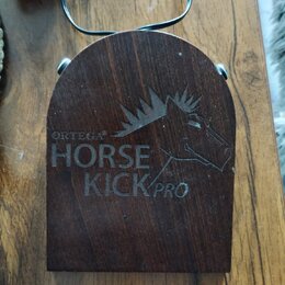 Tmavě hnědý dřevěný pedál s oblým horním okrajem. Na povrchu je vyryto logo koně a nápisy ORTEGA®, HORSE KICK PRO. Povrch vykazuje drobné škrábance a…