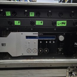 Černý rackový zesilovač značky NEXO s nápisem powered by YAMAHA a označením DIGITAL NXAMP4x4. Zařízení je umístěno v transportním kufru a má stříbrný…