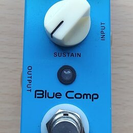 Modrý kytarový efekt s nápisem Blue Comp a značkou MOOGER. Na horní straně jsou dva černé otočné knoflíky s popisky LEVEL a ATTACK, přepínač Treble/N…