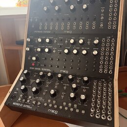 Tři černé modulační syntetizátory značky moog umístěné v dřevěném stojanu. Horní jednotka nese nápis SPECTRAVOX SEMI MODULAR SYNTHESIZER, prostřední…