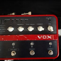 Červený efektový pedál značky VOX s kovovým šasi. Horní panel obsahuje pět bílých otočných ovátek s popisky FEEDBACK, TONE / SPEED, INTENSITY a MIX,…