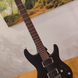 Černá elektrická kytara s matným povrchem a tmavým hmatníkem. Na hlavě je viditelné logo Ibanez. Nástroj má dva humbuckery, ovládací knoflíky a strun…