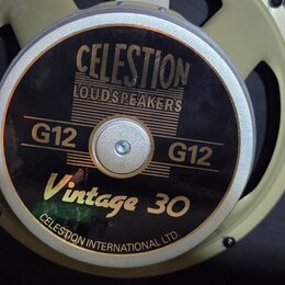 Fotografie zachycuje reproduktor s béžovým kovovým rámem. Na středovém krytu je černý štítek s nápisy CELESTION LOUDSPEAKERS, G12, Vintage 30 a v dol…