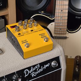 Žlutý kytarový efekt BOSS DD-200 HYBRID DRIVE umístěný na zesilovači Deluxe Reverb-Amp. Zařízení má několik ovládacích knoflíků, přepínač ON/OFF a ná…