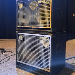 Dvě černé basové reproduktorové skříně naskládané na sebe. Horní skříň má stříbrnou mřížku s nápisy GOLIATH III a 8 OHM a logem značky Warwick. Spodn…