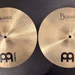 Dvě mosazné činely s viditelným broušením a hloubkovým rýhováním. Oba mají nápisy Byzance a logo MEINL. Na levém číneli je text 13" Medium Hihat, Bot…