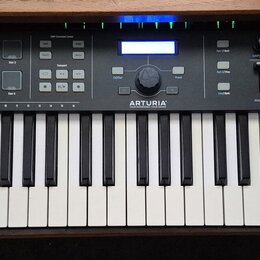 Černý MIDI kontrolér s klaviaturaí. Na levé straně je nápis KEYLAB 61 ESSENTIAL a uprostřed logo ARTURIA. Horní panel obsahuje podsvícené tlačítka, f…