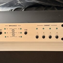 Stříbrný rackový přístroj s černým šasi. Na předním panelu je vpravo logo FRYETTE a nápis IMPEDENCE MATCHING AMP & CAB SELECTOR, vlevo dole je označe…