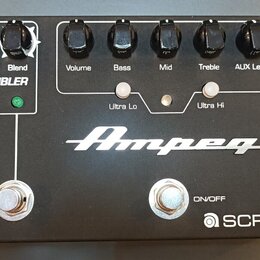 Černý kytarový předzesilovač s nápisy Ampeg a SCR-DI. Na horní straně jsou knoflíky s popisky Drive, Blend, Volume, Bass, Mid, Treble a AUX Level, dá…