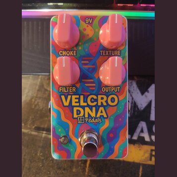 Kytarový efekt pedál s barevným, psychedrickým motivem v odstínech modré, červené a žluté. Na horní straně jsou čtyři růžové otočné knoflíky s popisk…