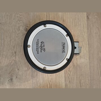 Kruhové elektronické bubnové plochy s bílým pleteným povrchem a černým gumovým okrajem. Na povrchu jsou nápisy Roland, MESH HEAD™ made by REMO a logo…