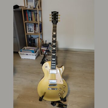 Elektrická kytara s tvarem singlecut, zlatavě žlutým lakem a hnědým hmatníkem. Na hlavě je bílý nápis Gibson. Nástroj má dva humbuckery, čtyři ovláda…