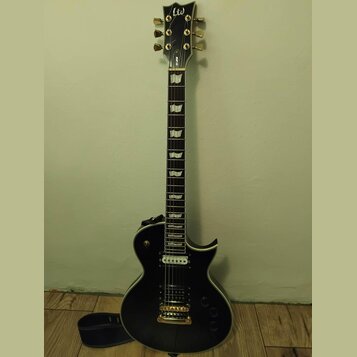 Černá elektrická kytara s tvarem typu Les Paul a zlatým hardwarem. Na hlavě je bílý nápis "LTD" a na hřdelníku označení "EC-250". Kytara má dva humbu…