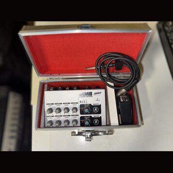 V otevřeném hliníkovém kufru s červeným vnitřkem je umístěn bílý mixážní pult. Na zařízení jsou nápisy MM8, Ashion a 8 CHANNEL MINI MIXER. Přístroj o…