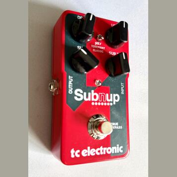 Červený efekt pedál s nápisy Subnup a tc electronic. Na horní části jsou čtyři černé ovládací knoflíky a texty POLY TONEPRINT CLASSIC, SUB, OUTPUT a…