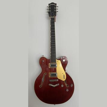 Tmavě červená polodublová elektrická kytara s dvěma f-otvory a žlutobílým pickguardem. Na hlavě je nápis GRETSCH a na pickguardu je logo GRETSCH. Nás…