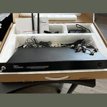 Černý rackový přístroj s nápisem the t.bone Free Solo Antenna Splitter a podtitulem UHF Antenna Distribute Implement. Zařízení leží v bílém polystyre…
