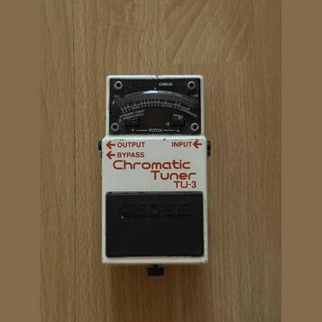 Bílý ladicí pedál s nápisy OUTPUT, BYPASS a Chromatic Tuner TU-3. V horní části je displej s označením CHECK, stupnicí od -50 do +50 a nápisy STREAM/…