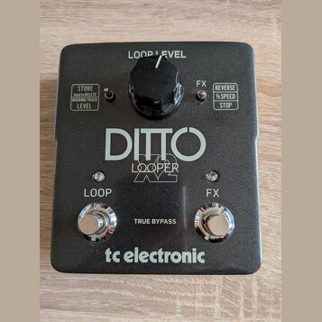 Černý kytarový pedál s nápisy DITTO LOOPER a tc electronic. Horní část obsahuje ovratový knoflík s popiskem LOOP LEVEL a dvě textová pole s funkcemi…