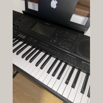 Černý digitální klavír značky YAMAHA, model PSR-SX700. Nástroj má bílé a černé klávesy, ovládací panel s displejem, několika tlačítky a voličem. Povr…