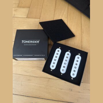 Černá krabice s nápisem TONERIDER GUITAR & BASS PICKUPS obsahuje tři bílé snímače s kovovými polosněma. Na spodní části krabice jsou texty SCATTERWOU…