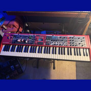 Červený digitální klavír s bílými a černými klávesami. Na levé straně je nápis nord stage 4 a v horní části jsou viditelné sekce Piano, Organ, Synth…