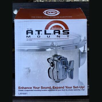 Krabice s příslušenstvím pro bicí s nápisy THE A.T.L.A.S MOUNT a logem Ludwig. Na obalu je text THE FIRST NAME IN DRUM HARDWARE, THE WORLD'S ONLY INT…
