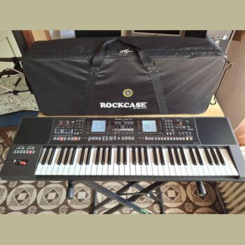 Černý digitální klavír s bílými klávesami, umístěný na černém X-stojanu. Na ovládacím panelu je nápis Roland XPS-10 a jsou vidět displeje, posuvníky…