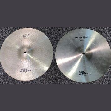 Dva stříbrné činely typu hi-hat s viditelným broušením. Na levém činele je nápis TOP ROCK HI HAT 14" / 35cm a logo Zildjian. Na pravém činele je nápi…