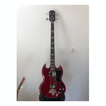 Čtyřstrunná basová kytara s červeným lesklým povrchem těla a černou hlavou. Na hlavě je nápis Epiphone. Tělo má charakteristický SG tvar, černý pickg…