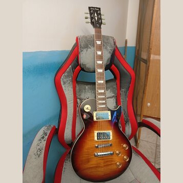 Elektrická kytara typu Les Paul s barevným přechodem od žluté k tmavě hnědé. Na hlavě hmatníku je bílý nápis Harley Benton. Nástroj má dva humbuckery…