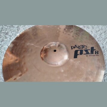 Kovový činel v měděné barvě s viditelným kovánívým zdobením ve formě drobných důlků. Na povrchu je černý nápis pAiste pst8 20" MEDIUM RIDE. Povrch vy…