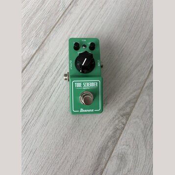 Zelený efekt pedál v kompaktním provedení. Na přední straně je nápis TUBE SCREAMER MINI a logo Ibanez. Pedál má jeden černý ovládací knoflík, stoupac…