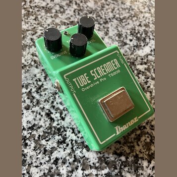 Zelený efekt pedál s kovovým šasi a třemi černými oválnými knoflíky. Na horní části je bílý nápis TUBE SCREAMER a pod ním menší text Overdrive Pro TS…