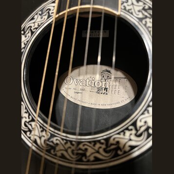 Detail zněkozvuku akustické kytary s ozdobným ornamentem kolem otvoru. Uvnitř je vidět štítek s nápisy Ovation, Model No. 1867 Legend, A KAMAN MUSIC…